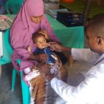 Faysal ha solo 11 mesi e soffre di malnutrizione acuta. Qui uno specialista in nutrizione di Azione contro la Fame gli prende la temperatura e misura la sua metà superiore del braccio per determinare il suo stato di salute. Immagine: Azione contro la fame in Somalia