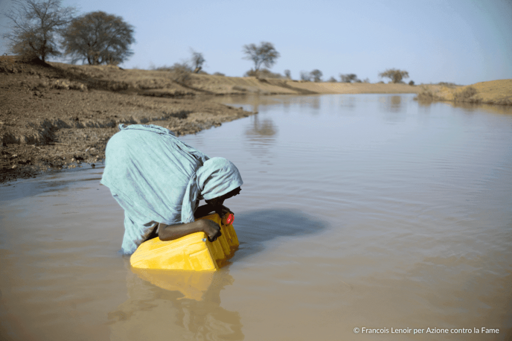 Bambino raccoglie acqua inquinata e contaminata dal fiume